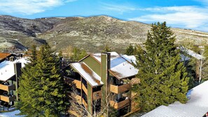 A mountain cabin with a sloped roof, wooden balconies, and a view of the surrounding landscape. - Powder Perch by Avantstay Hot Tub + Pool + Mountain-view Balcony Mins to the Slopes + Trails (Park City)
