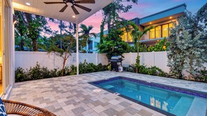 Une piscine dotée d’une terrasse carrelée, entourée de verdure et d’une clôture blanche.