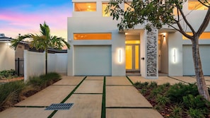 Une maison moderne à deux étages, dotée d’un garage, d’un jardin bien entretenu et offrant une vue sur un ciel dégagé.