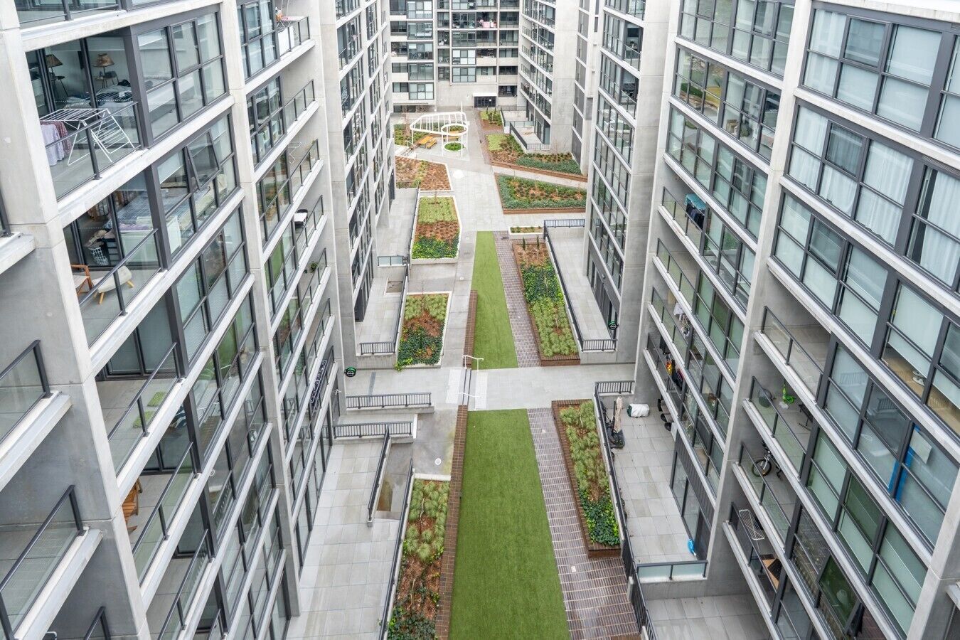A high-rise building with multiple floors, large windows, and a central courtyard with greenery.