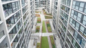 A high-rise building with multiple floors, large windows, and a central courtyard with greenery. - Inner North 1BR Near Braddon & Dickson (Lyneham)
