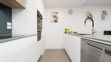 A modern kitchen with white cabinetry, stainless steel appliances, a black faucet, and a clock on the wall.