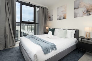 Ein Hotelzimmer mit einem großen Bett, Blick auf die Stadt durch ein Fenster und Kunstwerken an den Wänden.