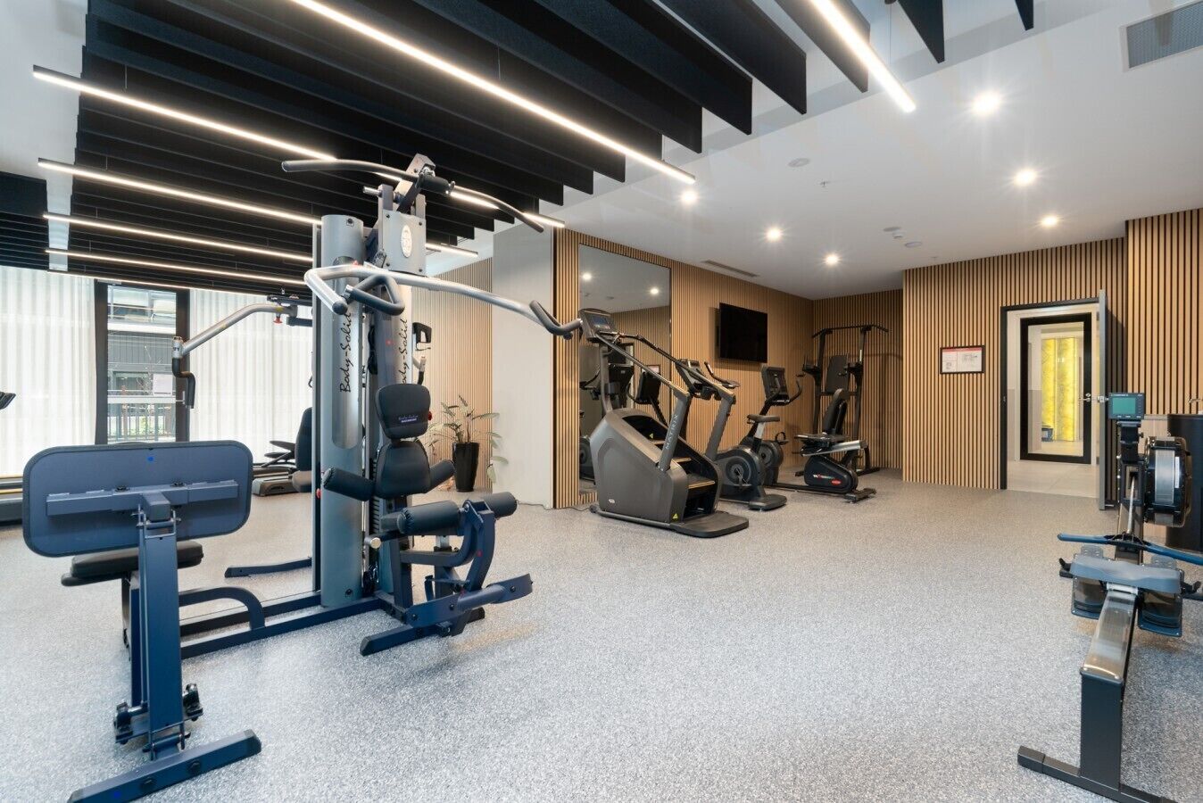 A modern gym with various exercise equipment, including a squat rack and treadmills.