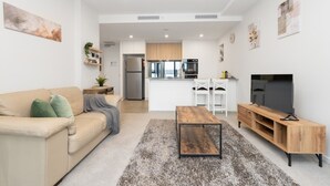 A modern living room with a sofa, coffee table, and TV stand. - Inner North 1BR Near Braddon & Dickson (Lyneham)
