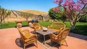 An outdoor patio with wicker furniture, a grill, and a view of a hilly landscape. - Solitude I by Avantstay Vineyard Views + Jetted Tub Paso Wine Country (Paso Robles)