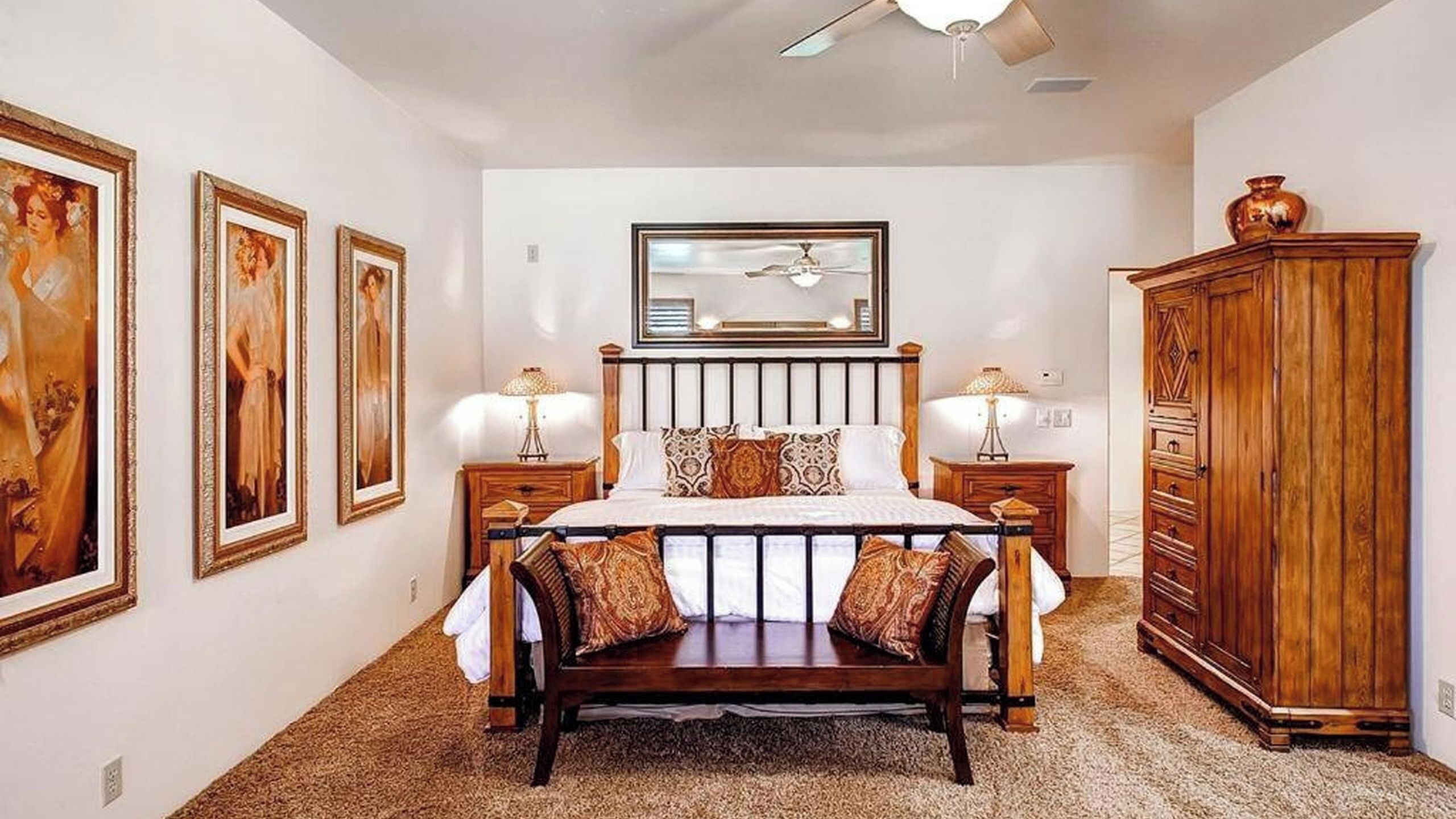 A bedroom with a bed, two nightstands, a mirror, and a wooden wardrobe.