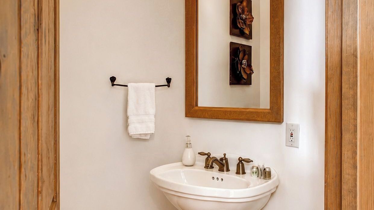 Une salle de bain avec un lavabo blanc, un miroir et un porte-serviettes.