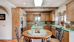 A kitchen with wooden cabinets, a round dining table, and a window with curtains. - Solitude I by Avantstay Vineyard Views + Jetted Tub Paso Wine Country (Paso Robles)