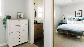 Ein Schlafzimmer mit Bett, Kommode, Nachttisch und Spiegel.