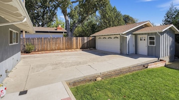 A residential garage with a tiled roof, a wooden fence, and a grassy yard.