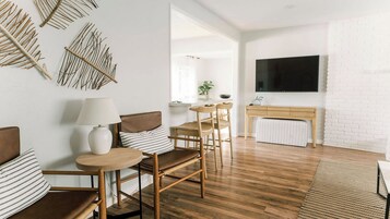 A modern living room with a sofa, chairs, a coffee table, a TV, and a fireplace.