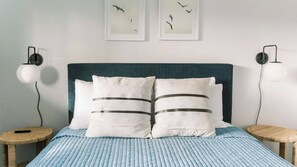 A bed with a blue-striped bedspread, two white pillows with gray stripes, and a teal headboard. There are two round nightstands with lamps, and two framed pictures on the wall. - Lake Park Landing by Avantstay Spa + Firepit + BBQ Near Atascadero Lake Park (Atascadero)