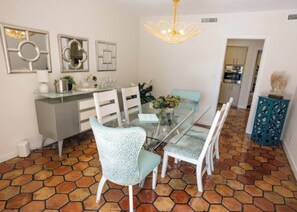 A dining area with a glass table, white chairs, and a decorative chandelier. -  New Property! The Hidden Catch.. 2-bdr house on the water and great for fishing (Lauderdale-by-the-Sea)