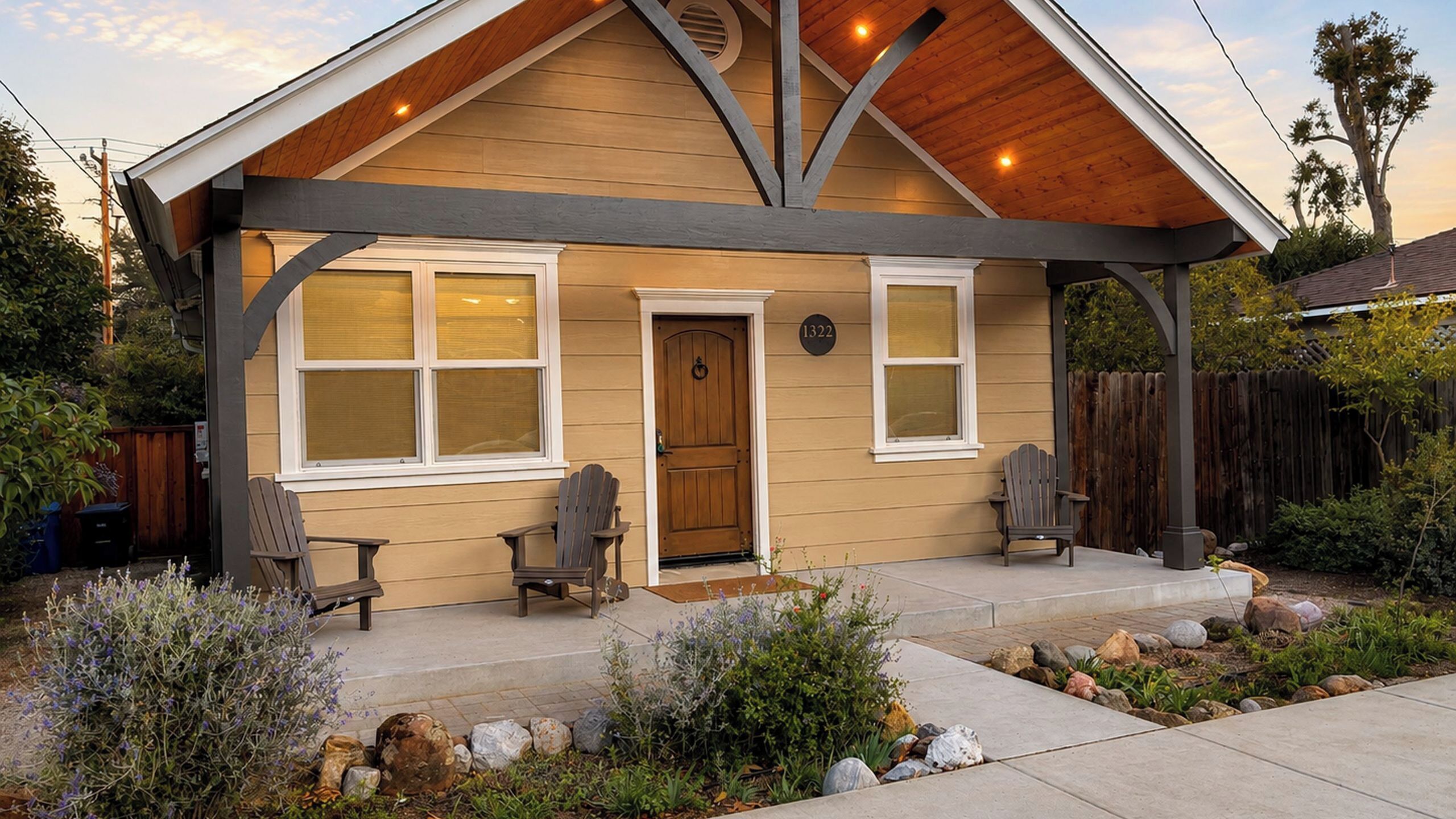 A two-story house with a covered porch, two windows, a door, and two Adirondack chairs.