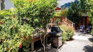 A patio area with a grill, outdoor seating, and a wooden structure. - Olive With a Twist by Avantstay Fenced Yard + Walk to Downtown Paso Robles (Paso Robles)