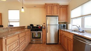 A kitchen with wooden cabinets, stainless steel appliances, and a window providing natural light. - Olive With a Twist by Avantstay Fenced Yard + Walk to Downtown Paso Robles (Paso Robles)