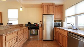 A kitchen with wooden cabinets, stainless steel appliances, and a window providing natural light. - Olive With a Twist by Avantstay Fenced Yard + Walk to Downtown Paso Robles (Paso Robles)