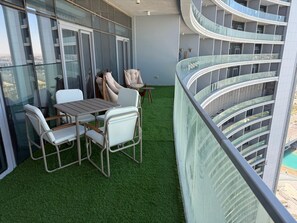 Ein Balkon mit Tisch und Stühlen, einem kleinen runden Tisch und einem Boden aus Kunstgrün.