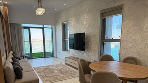 Ein modernes Wohnzimmer mit einer Couch, einem Esstisch, Stühlen, einem Fernseher und einem großen Fenster mit Blick.