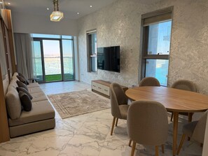 Ein modernes Wohnzimmer mit einer Couch, einem Esstisch, Stühlen, einem Fernseher und einem großen Fenster mit Blick.