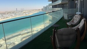 Ein Balkon mit Blick auf Strand und Stadtlandschaft, ausgestattet mit Stühlen und einem kleinen Tisch.