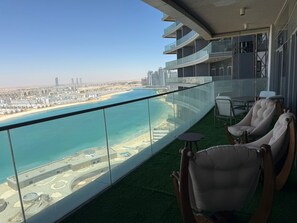 Ein Balkon mit Blick auf Strand und Stadtlandschaft, ausgestattet mit Stühlen und einem kleinen Tisch.