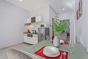 A modern kitchen with white cabinets, a stainless steel refrigerator, and a microwave. - The 1 Bedroom "Four" with large pool (Muang Pattaya)