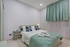 A bedroom with a bed, nightstand, bedside lamp, and a wall-mounted curtain. - The 1 Bedroom "Four" with large pool (Muang Pattaya)