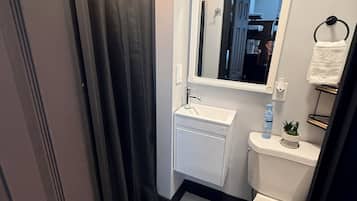 A bathroom with a toilet, sink, mirror, and shower curtain.