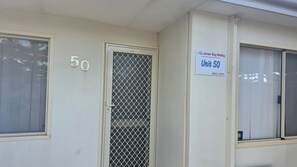 A building facade with a number '50' sign, a unit number sign for 'Unit 50', and a window with a mesh screen.