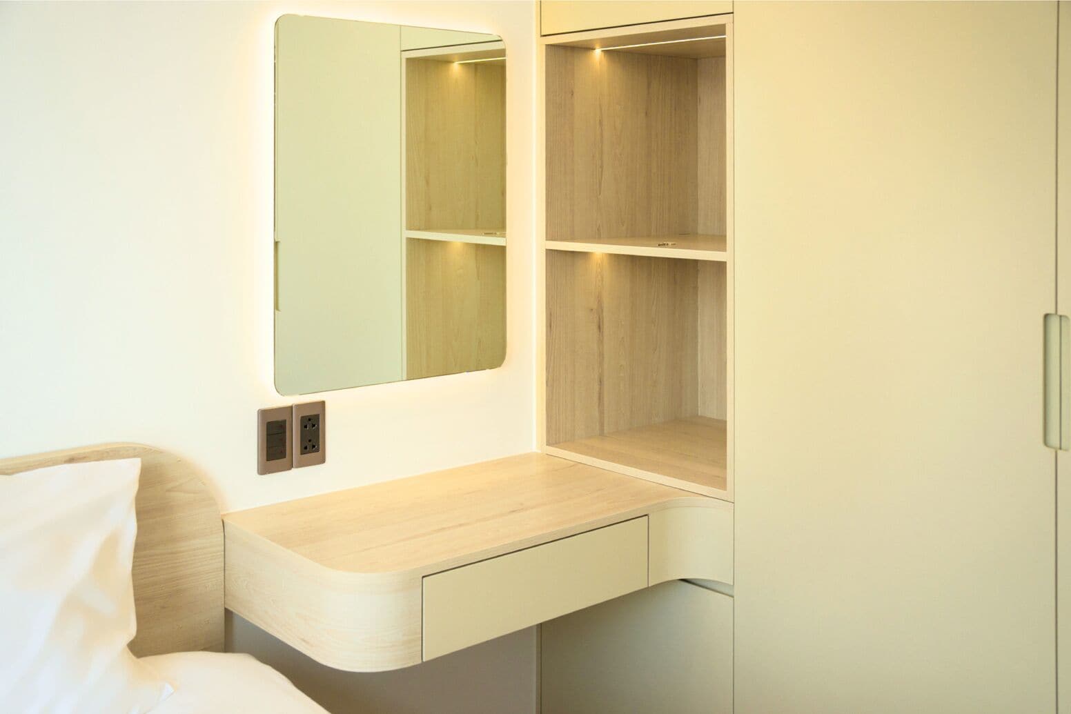 A modern bathroom with a built-in sink, mirror, and wooden shelving unit.