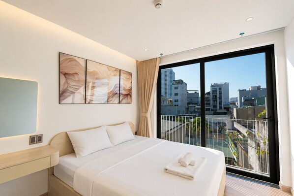 A modern hotel room with a large bed, a city view balcony, and artwork on the wall. - LUANDA APARTMENT (Da Nang)