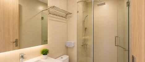 A modern bathroom with a glass shower enclosure, a white sink, and a mirror.