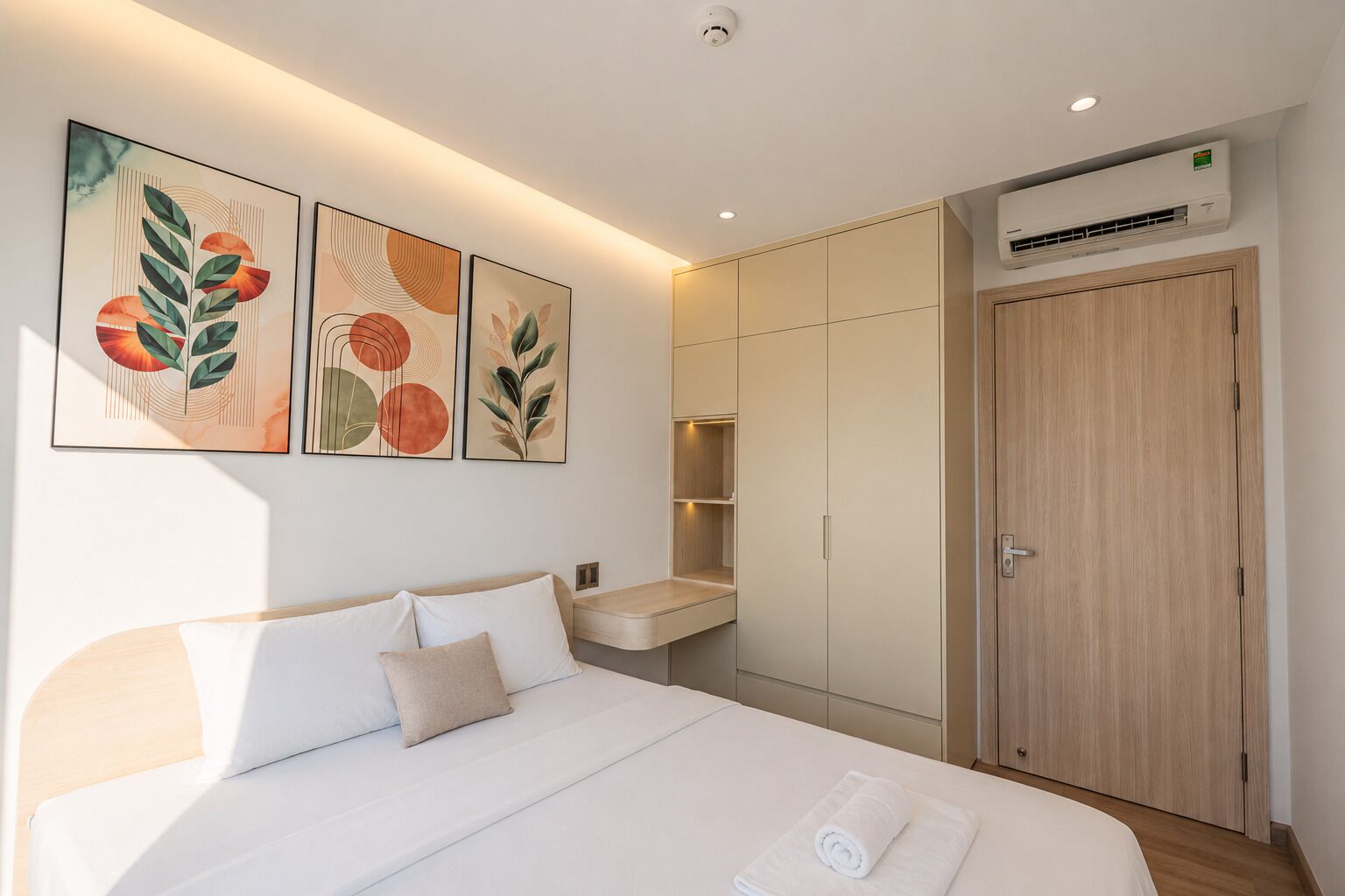A modern bedroom with a bed, bedside tables, a wardrobe, and wall art.