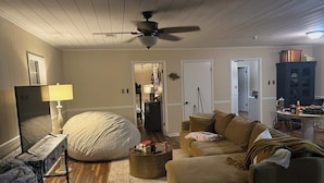 A living room with a ceiling fan, a bean bag, two couches, a coffee table, and a lamp.