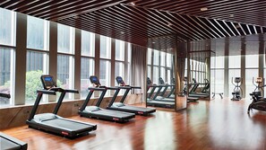 A gym with multiple treadmills aligned in rows, large windows, and a wooden ceiling. - Baoding Hotel of HangzhouGrandNewCentury (Hangzhou)
