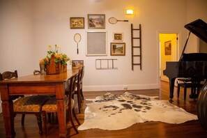 A dining area with a wooden table and chairs, a cowhide rug, and a piano.