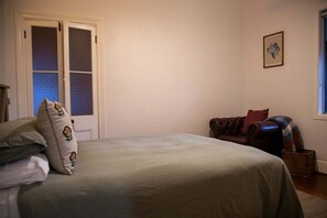 A bedroom with a bed, a window, a door, and a small piece of wall art. - The Farmhouse at Levenvale Farm (Bellingen)