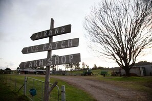 A wooden signpost with directions to 'AIRLINE', 'THE PATCH', and 'FARM SHOP'. - The Farmhouse at Levenvale Farm (Bellingen)