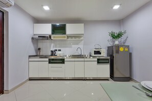 Une cuisine moderne avec des meubles blancs, des appareils en acier inoxydable et un tapis vert sur le sol.