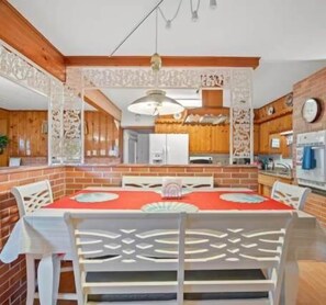 A dining area with a red tablecloth, white chairs, and a brick wall. - Pet Friendly 3BR Home w/ Pool & Easy I75 Access (Valrico)