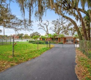 A pathway leading to a building with a fenced yard and trees. - Pet Friendly 3BR Home w/ Pool & Easy I75 Access (Valrico)