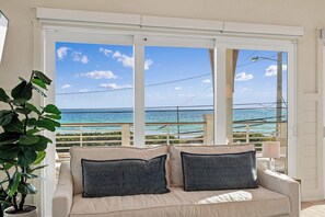 A balcony with a view of the ocean, a beige sofa with cushions, and a potted plant. - Casa Elcoqui | LUX Gulf Views, Pool + Spa, Sleeps 16 (Panama City Beach)
