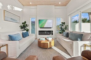 A modern living room with two sofas, a coffee table, a flat-screen TV, and a fireplace. - Casa Elcoqui | LUX Gulf Views, Pool + Spa, Sleeps 16 (Panama City Beach)