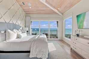 Un dormitorio con una cama grande, un televisor y vista al mar.
