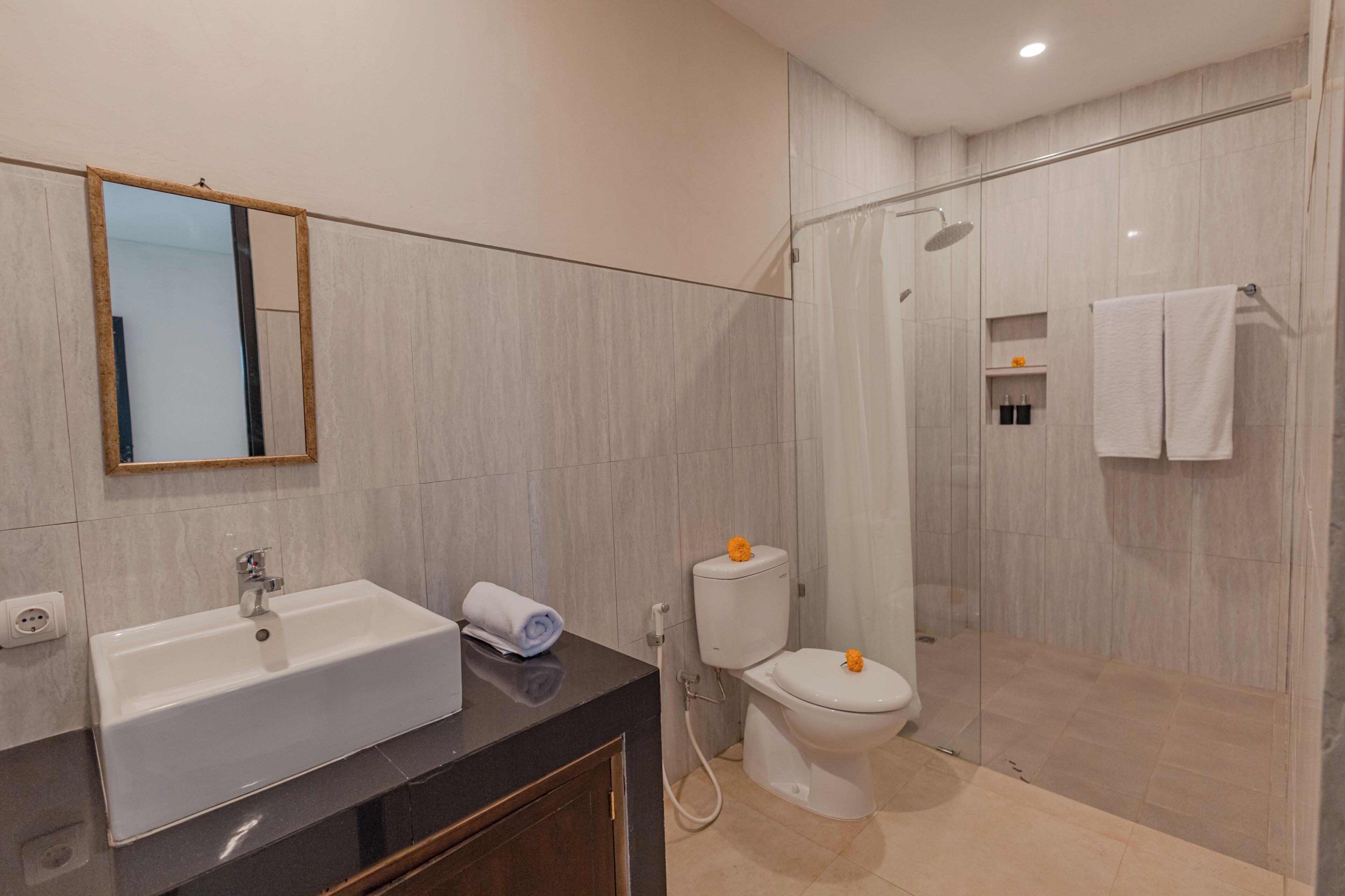 Un baño moderno con lavamanos, espejo, inodoro y ducha.