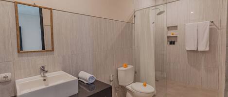 Un baño moderno con lavamanos, espejo, inodoro y ducha.