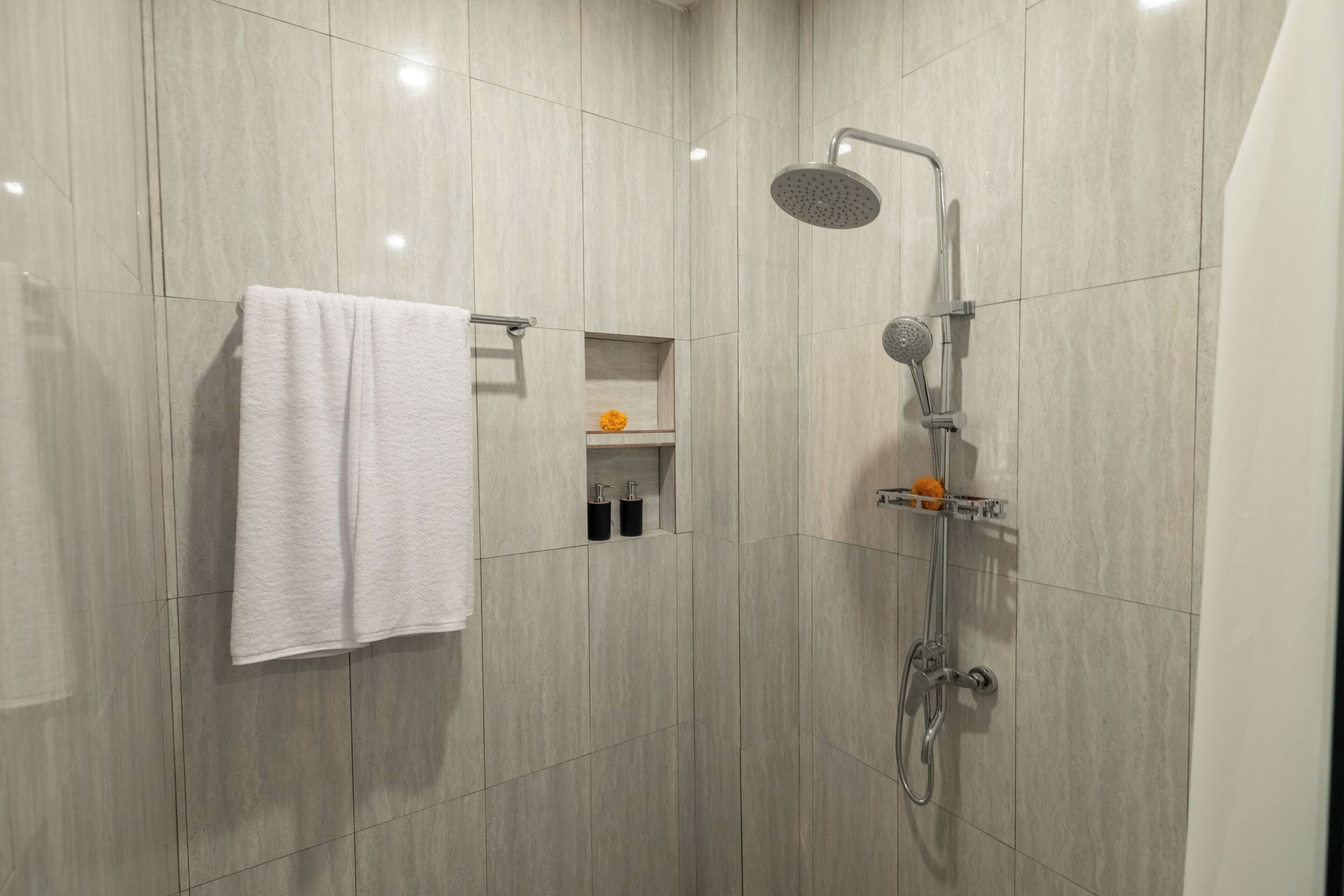 Ein modernes Badezimmer mit Dusche, Handtuchhalter und einem kleinen Ablagefach für Pflegeprodukte.