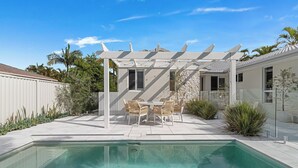 Ein Pool mit Pergola und einer Sitzgruppe im Freien.